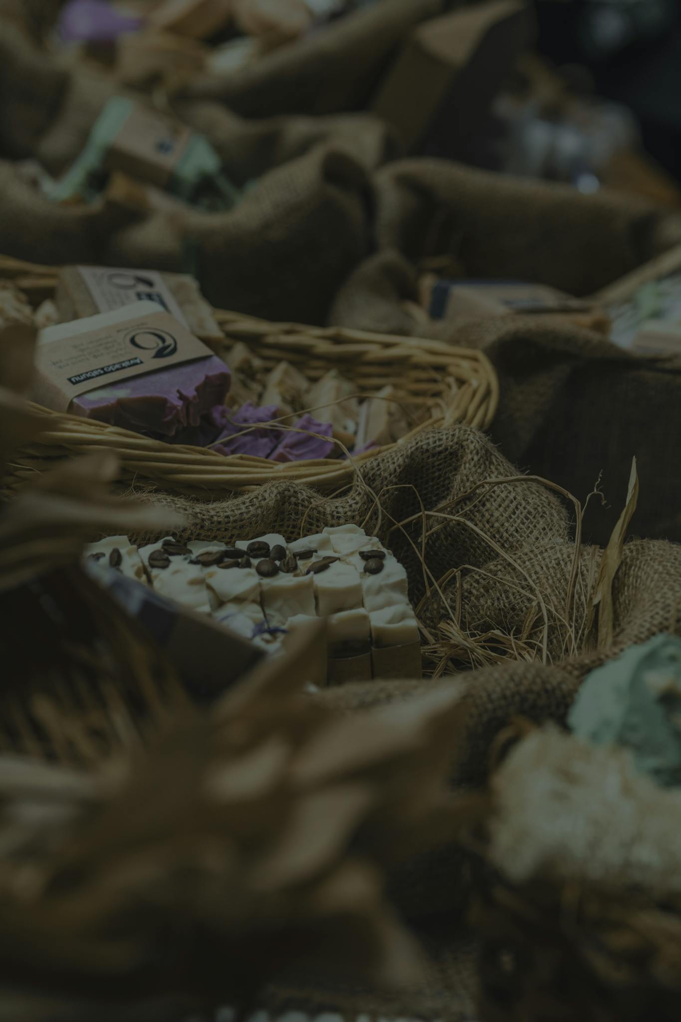 Close-up of handmade soaps in a rustic basket setting, showcasing textures and colors.
